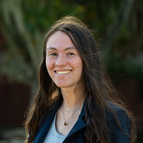 Hannah Duckwitz wearing a blazer standing outside of Dickinson Hall and smiling for a headshot.