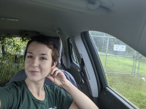 Smiling researcher in a vehicle with plants in the background